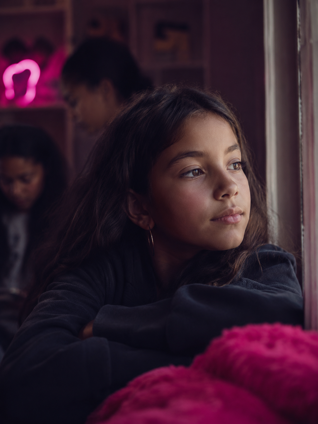 A girl sitting apart from the group, looking out a window