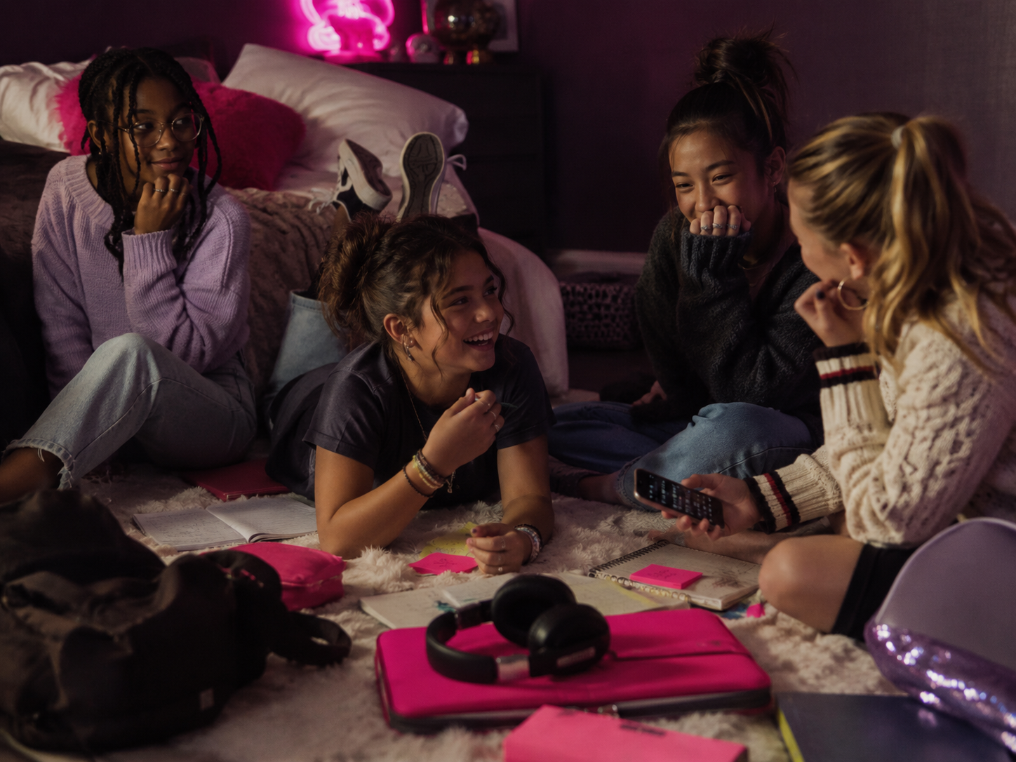 Girls on a bedroom floor looking at a phone together